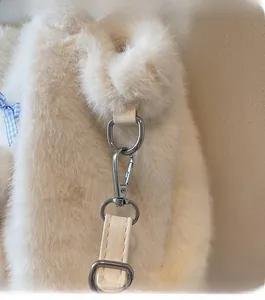 Close-up of premium silver metal hooks and hardware on a plush cream faux fur tote bag