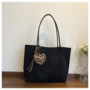 Close-up of black large tote bag with leopard heart charm and tassel detail