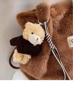 Macro-opname van een teddybeer pluche hanger met bruine trui aan een zachte handtas
