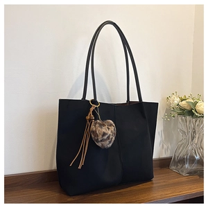Detail of black suede tote bag with leopard print pom-pom and brown leather tassels