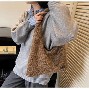 Detailed macro view of the fluffy brown faux fur texture and black brand label on a tote bag