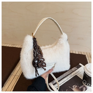 Detailaufnahme der flauschigen weißen Kunstfell-Handtasche mit modischem Anhänger