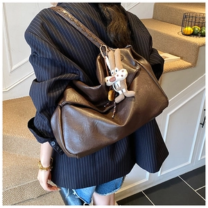 Detail of dark brown leather tote bag with a retro rabbit charm and soft texture
