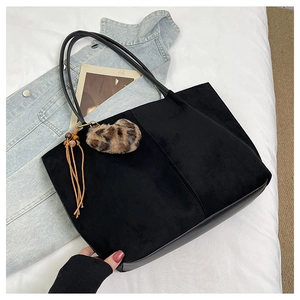Close-up of black tote bag with suede texture, fringe tassel and leopard heart charm