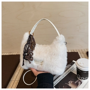 Detail der weißen Kunstpelz-Handtasche mit Ledergriff und schickem Buchstaben-Anhänger