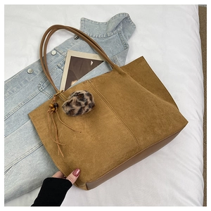 Detailed view of caramel suede tote bag with leopard fur ball and wooden bead charms