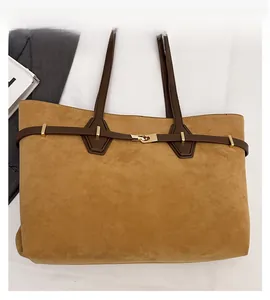 Detail of brown suede tote bag with leather strap and golden metallic buckle accent