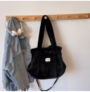 Detail van zwarte faux fur draagtas met pluche textuur hangend aan een houten rek