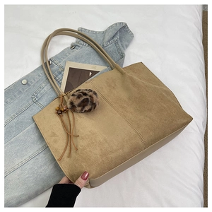 Detail of tan suede tote bag with leopard faux fur pom-pom and beaded tassel detail