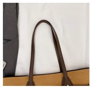 Detailed macro view of the comfortable leather handles on a brown suede tote bag