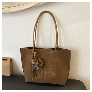 Detail of leopard embossed texture on brown suede tote bag with heart plush charm