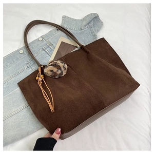 Detail view of large dark brown tote bag with retro tassel and leopard print charm