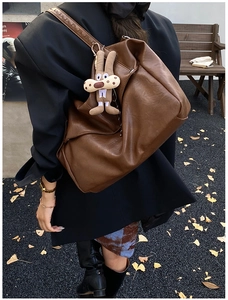 Close-up of brown large capacity shoulder bag with a cute rabbit pendant on a park bench