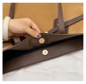 Detail of brown suede tote bag featuring a strong gold magnetic snap closure