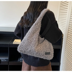 Detail of grey faux fur shoulder bag with plush texture and minimalist brand label
