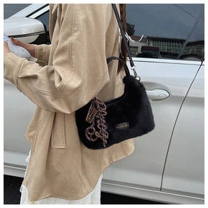 Detail der schwarzen Kunstpelz-Tasche mit Slogan-Label und kreativen Anhängern