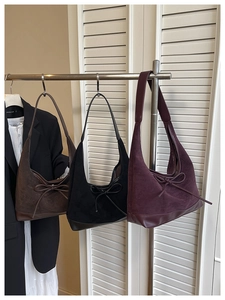 Detail of vintage tote bags in brown, black, and burgundy with suede finish and bow ties