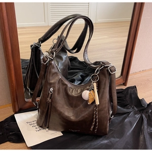 Detail of dark brown faux leather tote with vintage texture and sport-themed pendants