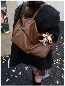Detail of deep brown tote bag with pleated leather texture and plush animal charm
