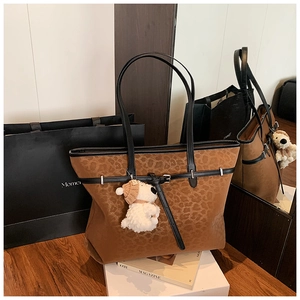 Detail view of leopard print tote bag with brown trim and cute plush puppy charm