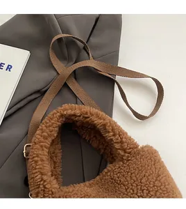Detail of plush brown bucket bag showing woven strap and golden adjustable metal buckle