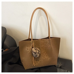 Detail of brown suede leopard print tote bag with removable faux fur pom-pom charm accessory
