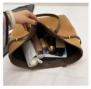 Spacious brown suede tote bag interior filled with tablet, umbrella and cosmetics