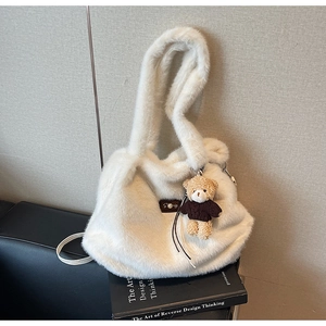 Detail van witte pluche schoudertas met een schattige teddybeer hanger en zachte vacht