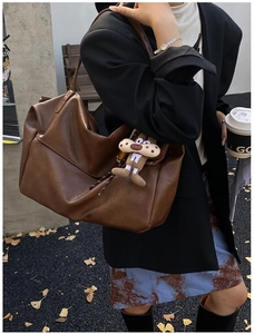 Detailed view of deep brown large tote bag with a cute bear charm on an outdoor model