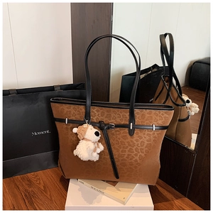 Detail of leopard print tote bag with brown faux suede texture and plush bear charm