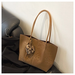 Detail of leopard print tote bag with heart-shaped plush charm and tassel accent
