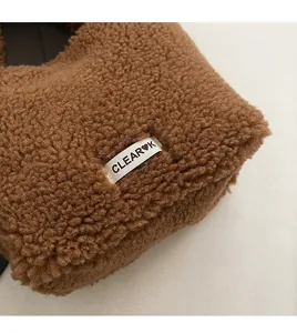 Detail of brown teddy fleece fabric with engraved silver metal brand logo on the bag