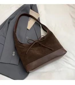 Detail of vintage brown suede tote bag with bow accent on stylish blazer background