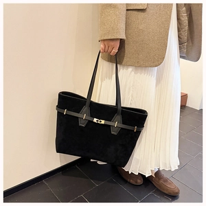 Detail of black suede tote bag featuring elegant gold metal lock and vintage strap design