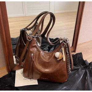 Close-up of retro brown faux leather tote bag with tassel zipper and sports charms