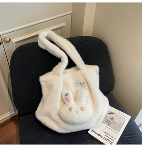Detail of plush rabbit face with carrot embroidery and blue bow on a white tote bag