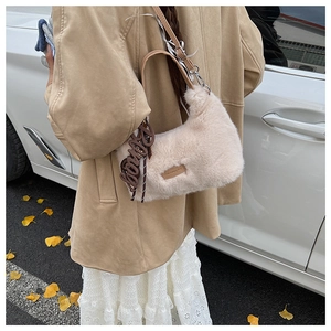 Details einer beigen Plüschtasche mit braunem Markenetikett und Bonny-Anhänger