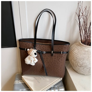 Close-up of leopard print tote bag featuring black handles and a cute bear charm accessory