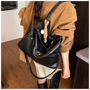 Close-up of black leather tote bag with silver buckle and brown plush pendant