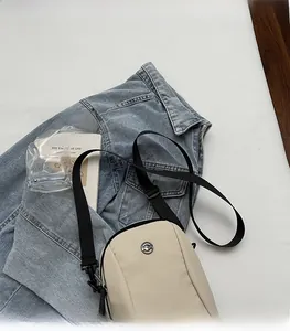 Detail of adjustable black nylon strap and silver logo on beige crossbody phone bag