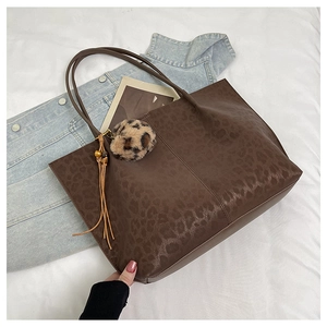 Detail of leopard print tote bag featuring brown tassel and faux fur pompom charm