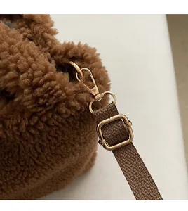 Detail of brown teddy fur bag featuring golden metal hooks and adjustable strap