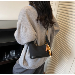 Détail du sac à main noir en toile et cuir avec perles vintage porté par un mannequin