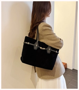 Detail of black suede tote bag showing golden buckle and textured side profile view