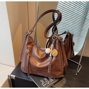 Detail of dark brown tote bag featuring baseball charms and vertical zipper pocket