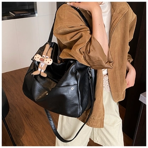 Detail of black faux leather tote bag with a plush bunny charm on the shoulder strap