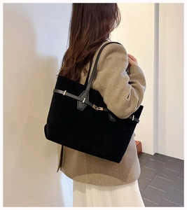 Detailed side view of a large black suede tote bag with elegant gold buckle strap accents