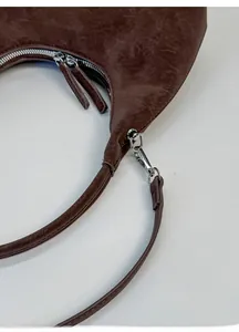 Detail view of the vintage brown dumpling bag showing the detachable metal shoulder strap