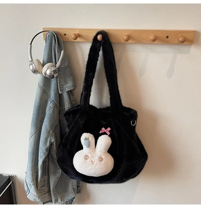 Detail of black faux fur tote bag featuring a cute plush bunny charm with pink bow