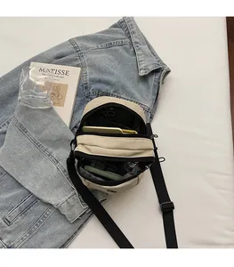 Detail of multi-compartment oxford crossbody bag showing interior space for phone and wallet